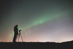 person taking photo of norther lights using tripod