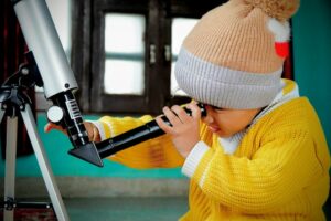 child looking through a telescope lens